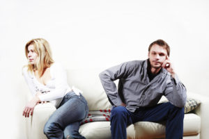 Man and woman sitting on the couch and turning away from each other